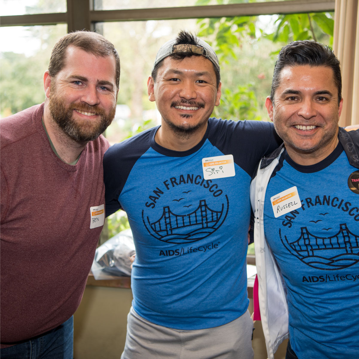 Three happy people volunteering for Aids/LifeCycle. The are wearing volunteer name badges