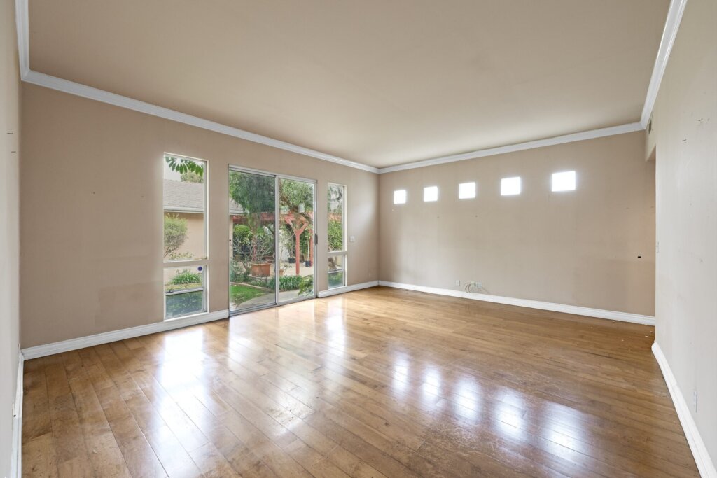 Before: an empty bedroom with dated wall colour and a sliding door to the garden