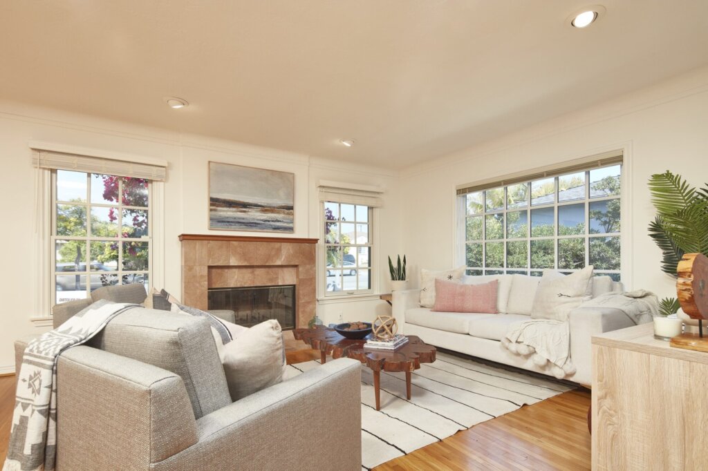 After: the same living room painted white and staged with sofas around the fireplace