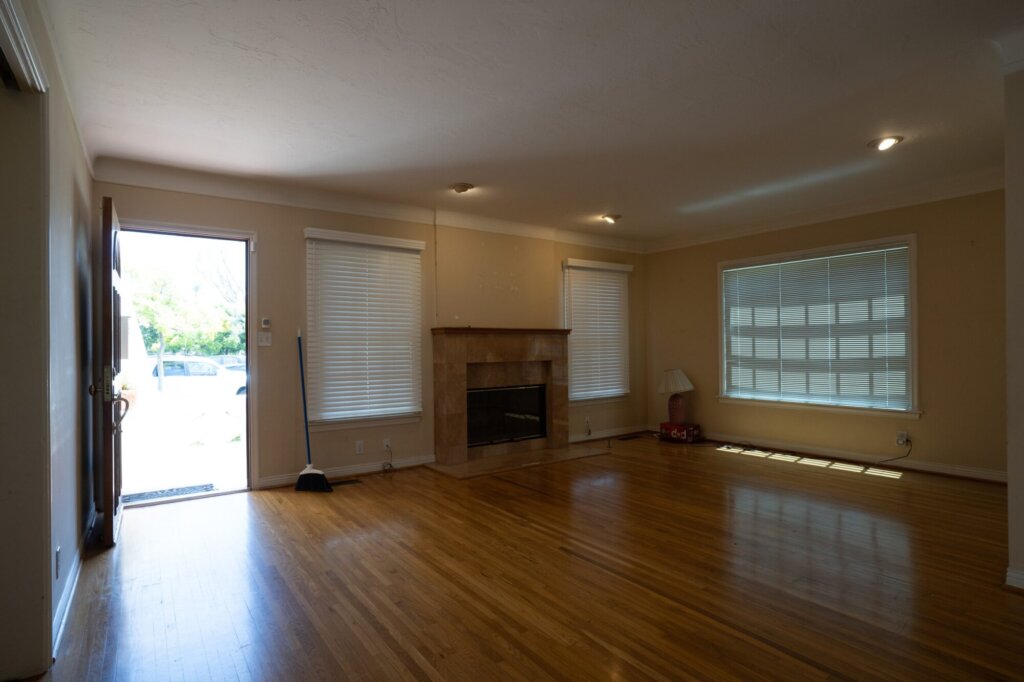 Before: an empty living room with a dated wall colour and a plain fireplace