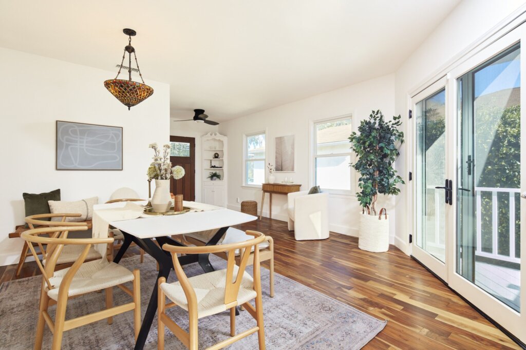 After: the same dining room painted bright white and staged with a wood table and art